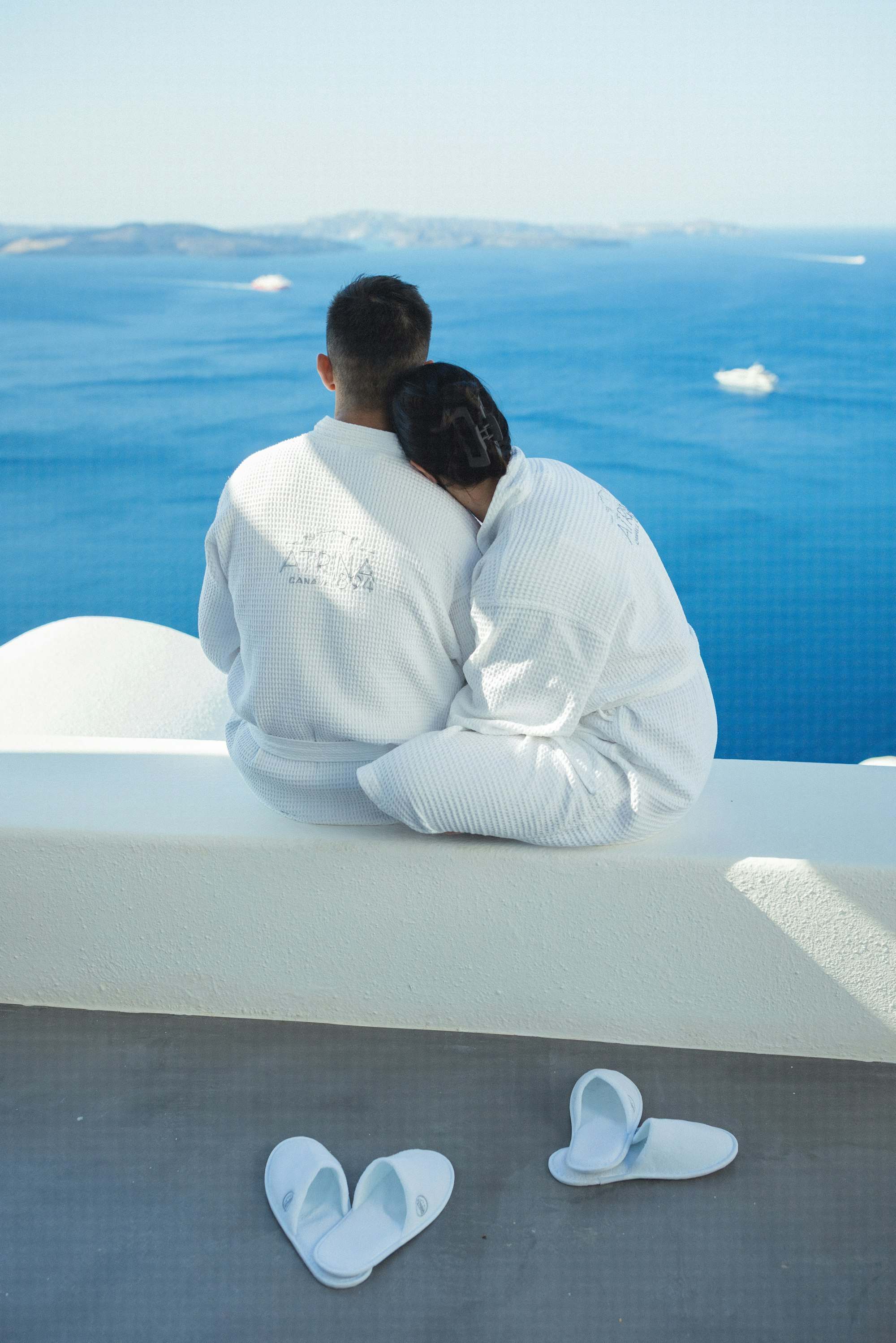 Couple in robes on a terrace overlooking the sea