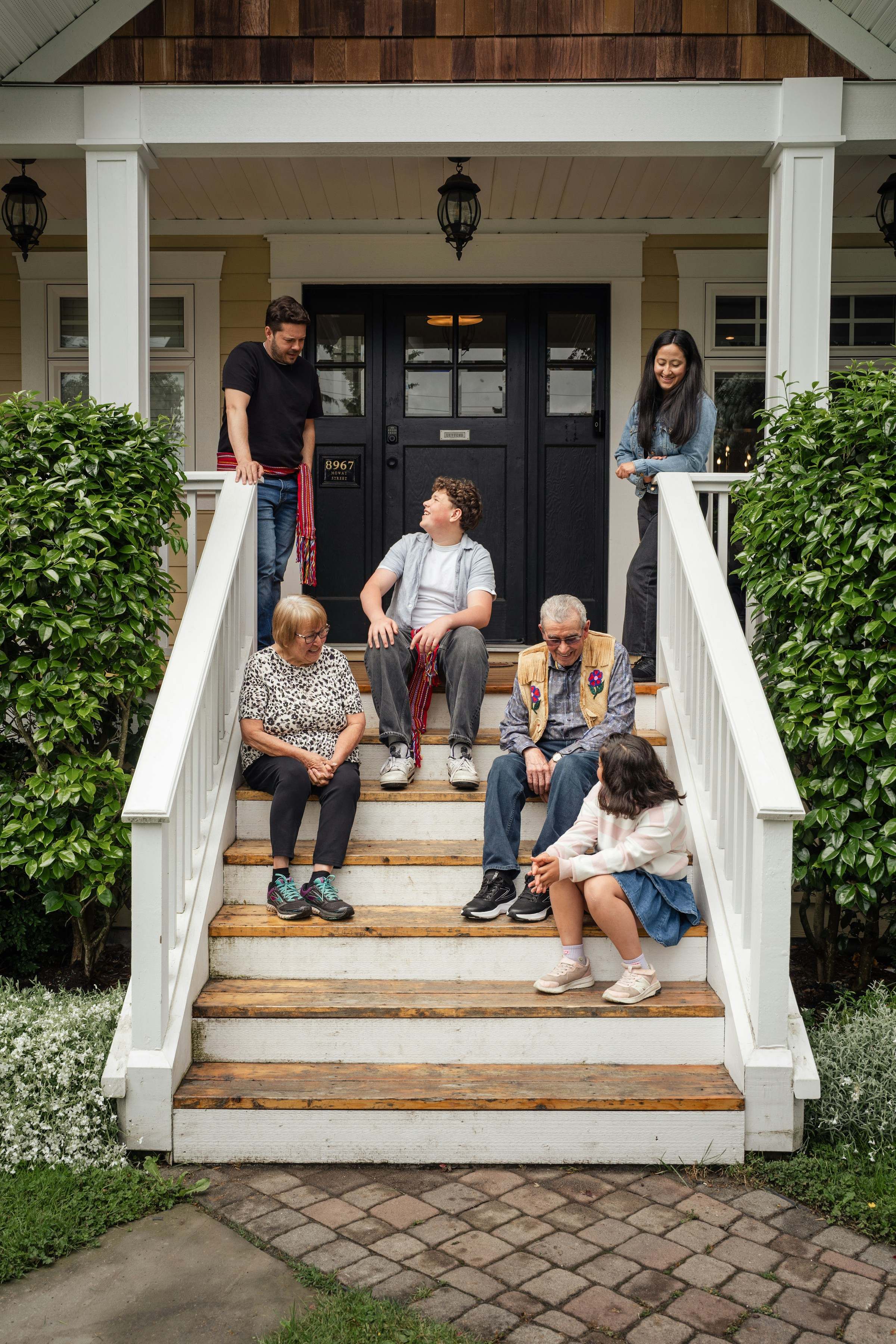Three generations of a family sitting together on the front steps of their home