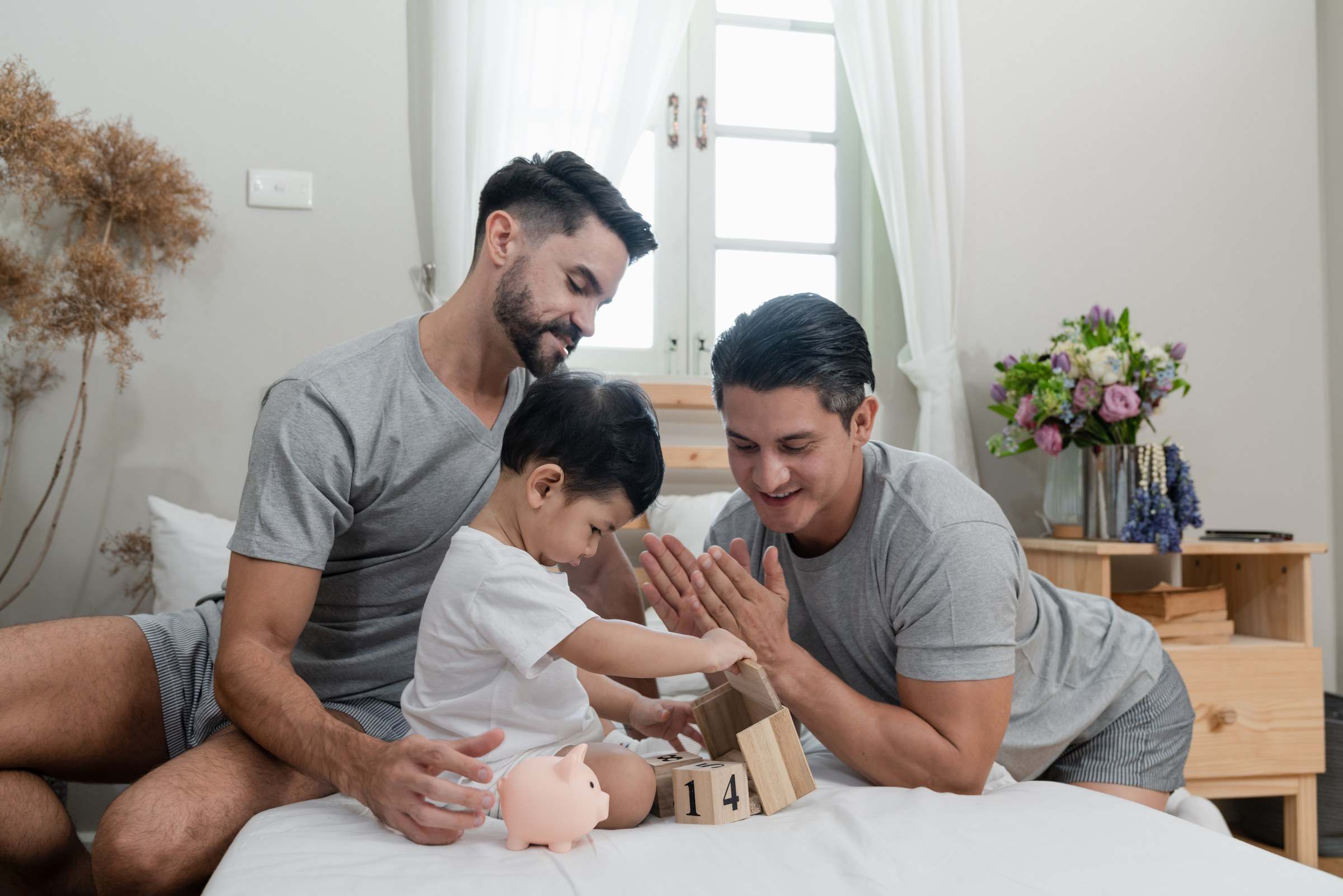Two dads playing with their young son at home