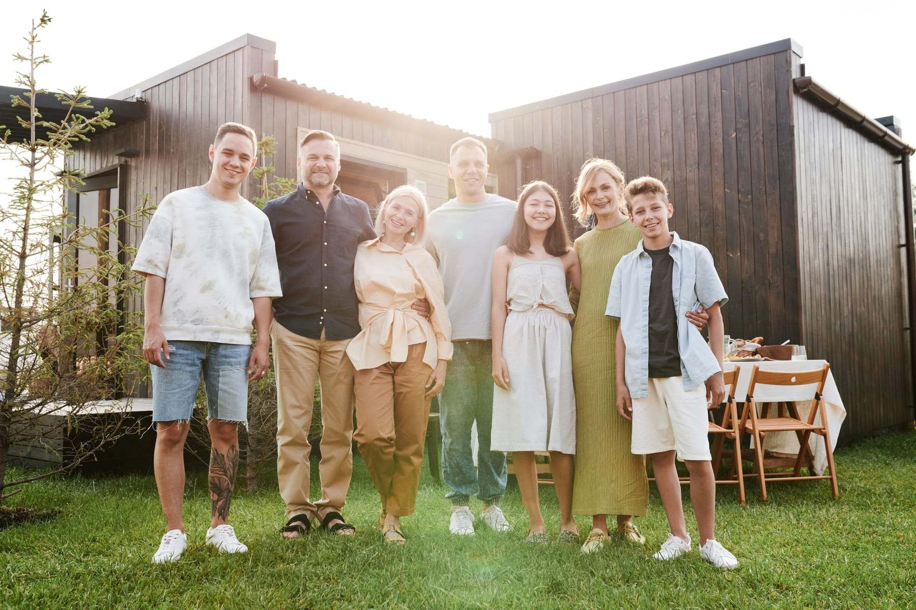 Extended family standing together on the lawn outside a modern home