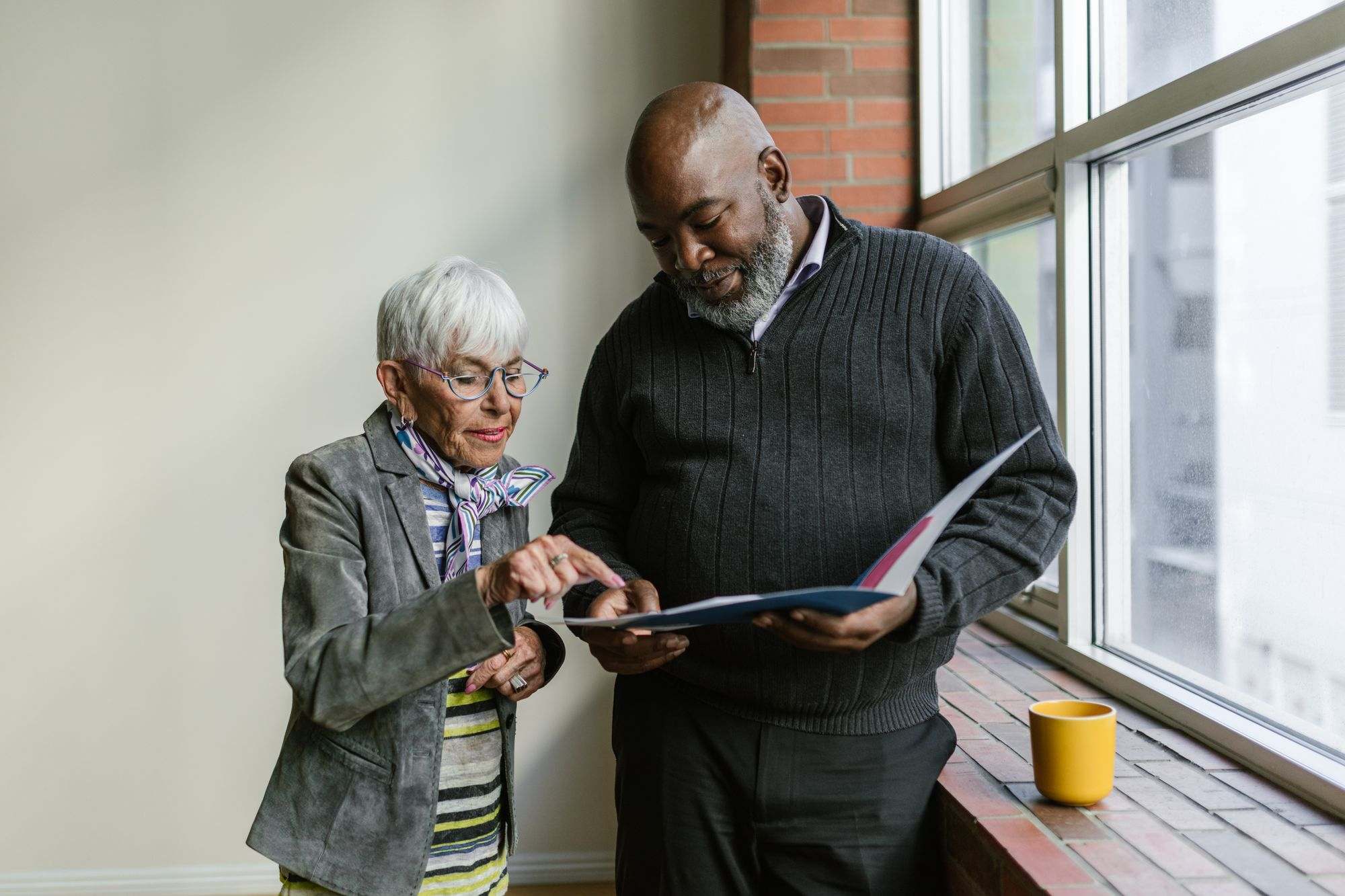 Older couple by a window reviewing a folder together